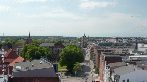 Backwards fly above historic town. Old university building and Kropeliner Tor on end of street photo