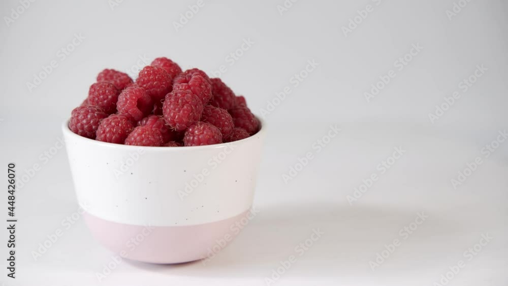 Plate with delicious fragrant raspberries on a white background. The plate revolves around its axis. Delicious and healthy dessert. Close-up Plate with delicious fragrant raspberries on a white background. The plate revolves around its axis. Delicious and healthy dessert. Close-up