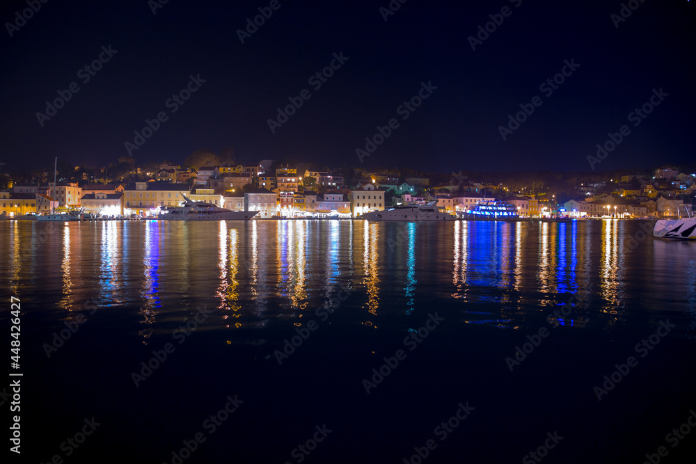 Night view of Mali Lošinj harbor and marina in medieval old town Mali Lošinj. Mooring luxury yachts, boats and other vessels on the pier. A summer vacation in a Croatian islands at Adriatic sea.