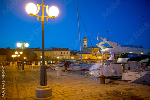 Evening view of Krk Harbor and marina in medieval old town Krk. Mooring yachts, boats and other vessels on the pier. A summer vacation in a Croatian islands at Adriatic sea. Island Krk, Croatia. photo