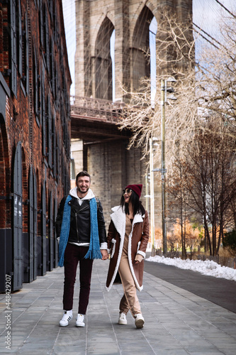 Canvas Print Young caucasian couple of tourists walk at Brooklyn bridge in New York city
