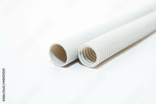 PVC rigid and flexible electrical conduit isolated on white background. Plastic curvilinear hoses. White corrugated pipe for installation of electrical cable 