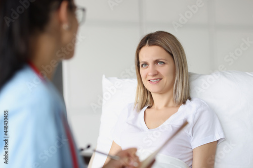 Doctor communicates with bedridden patient in hospital ward