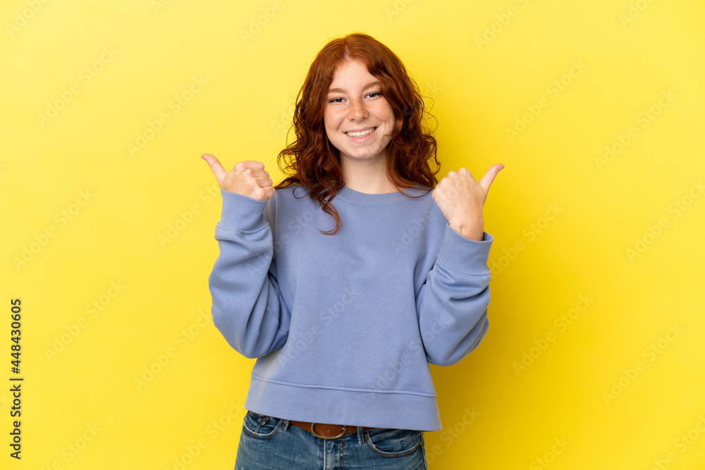 Teenager reddish woman isolated on yellow background with thumbs up gesture and smiling Teenager reddish woman isolated on yellow background with thumbs up gesture and smiling
