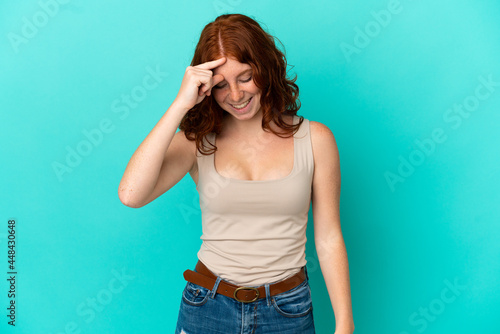 Teenager reddish woman isolated on blue background laughing