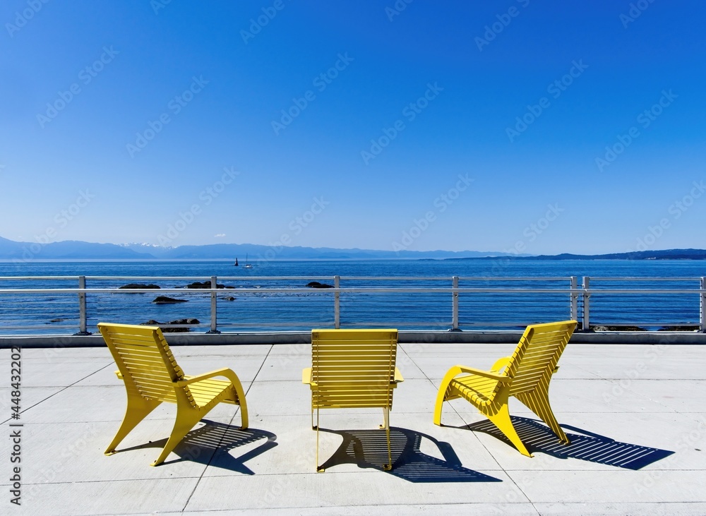 Yellow Adirondack chairs adorn the promenade near Ogden Point in Victoria BC