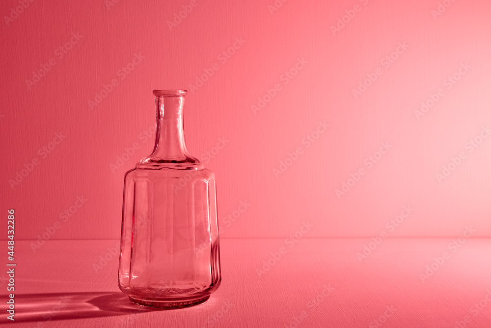 Glass empty open bottle with copy space. Graphic still life with light and shadow in red light. The concept of glass containers, recyclable materials or alcoholism. Large creative vase. Open flask Glass empty open bottle with copy space. Graphic still life with light and shadow in red light. The concept of glass containers, recyclable materials or alcoholism. Large creative vase. Open flask