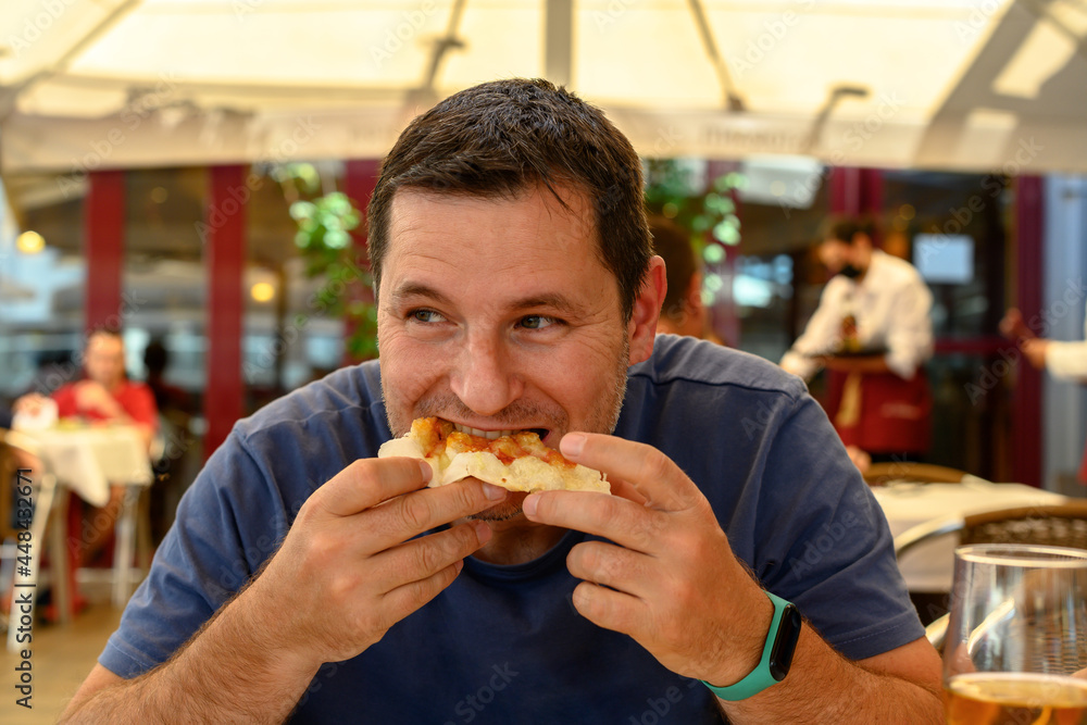 Mature man eating a slice of pizza in a restaurant. Medium shot Mature man eating a slice of pizza in a restaurant. Medium shot