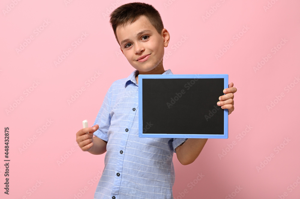Isolated portrait on pink background of a schoolboy with chalk and chalkboard in his hands. Back to school. Concepts Isolated portrait on pink background of a schoolboy with chalk and chalkboard in his hands. Back to school. Concepts