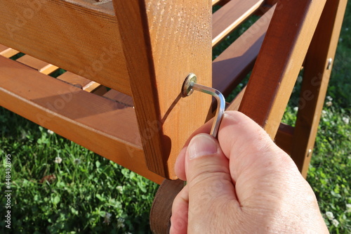 Fotografie Close-up of a hand tightening a loose screw on a garden chair