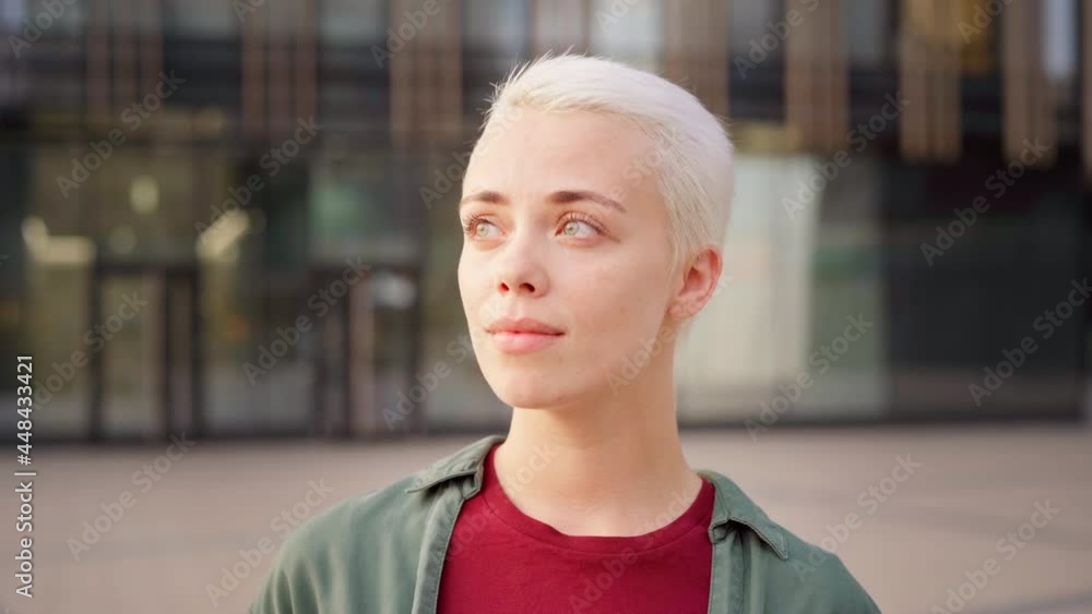 Head and shoulders portrait of young woman with short blonde hair thinking outdoors. Female looking away with hope and belief in her green eyes Head and shoulders portrait of young woman with short blonde hair thinking outdoors. Female looking away with hope and belief in her green eyes