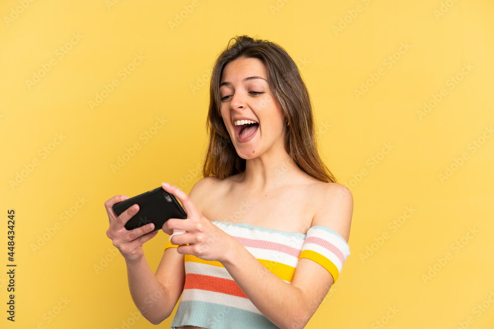 Young caucasian woman isolated on yellow background playing with the mobile phone Young caucasian woman isolated on yellow background playing with the mobile phone