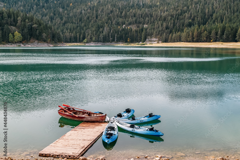 Φωτογραφία The lake in the mountains, surrounded by pine forest, boats on the lake reflected in water, calm and tranquility