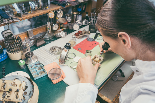 Watchmaker woman absorbed in her delicate work wearing spectacles photo
