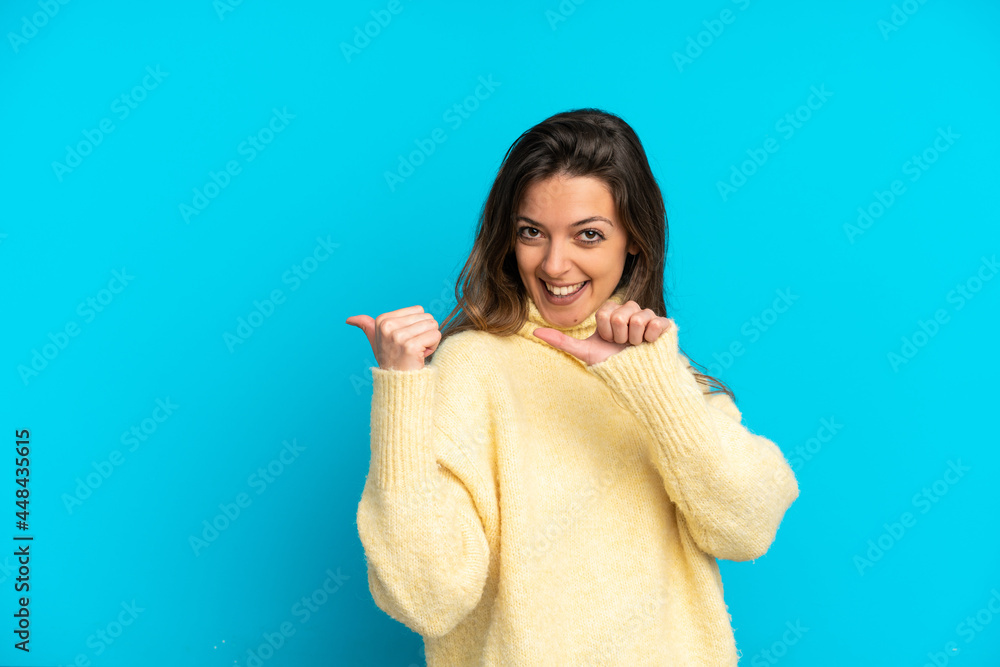 Young caucasian woman isolated on blue background pointing to the side to present a product Young caucasian woman isolated on blue background pointing to the side to present a product