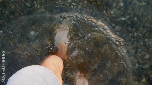 Man walks in the water on the beach in summer. First person view
