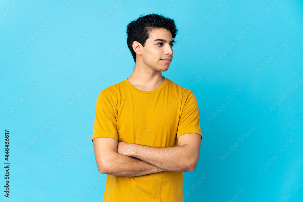 Young Venezuelan man isolated on blue background looking to the side Young Venezuelan man isolated on blue background looking to the side