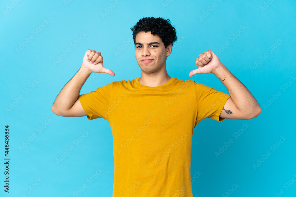 Young Venezuelan man isolated on blue background proud and self-satisfied Young Venezuelan man isolated on blue background proud and self-satisfied