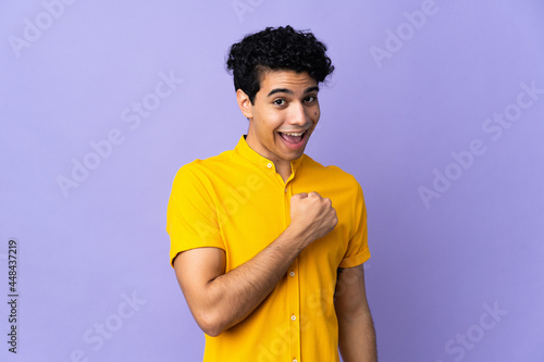 Young Venezuelan man isolated on purple background celebrating a victory