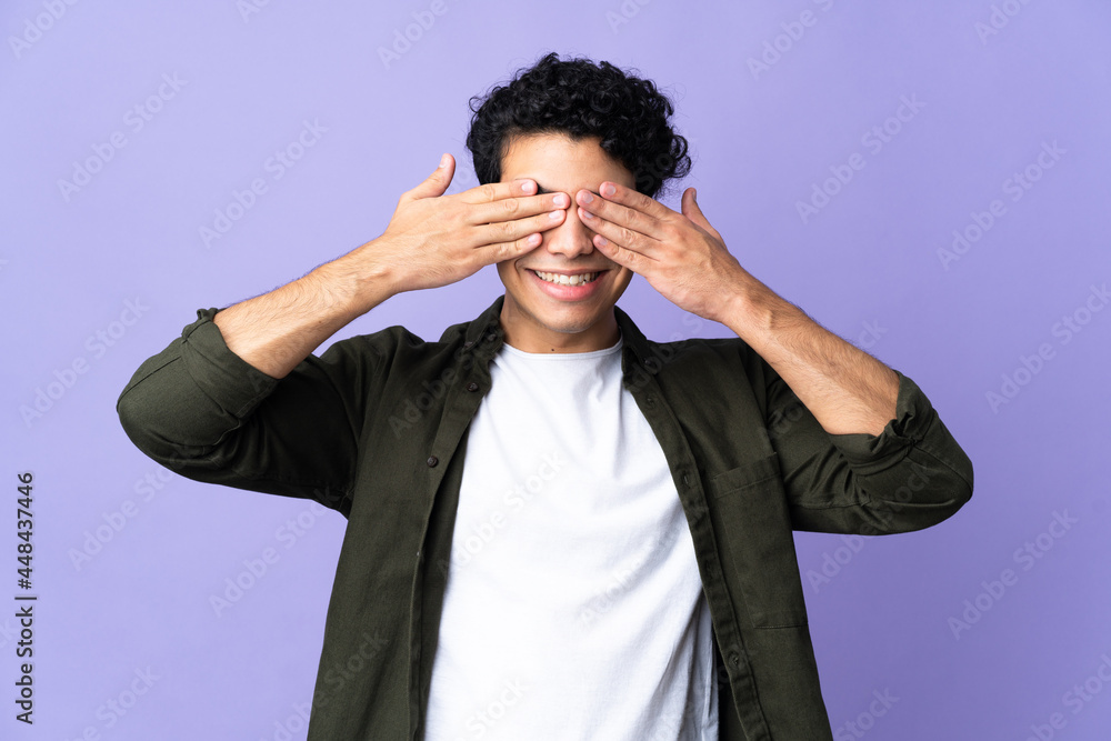 Young Venezuelan man isolated on purple background covering eyes by hands and smiling Young Venezuelan man isolated on purple background covering eyes by hands and smiling