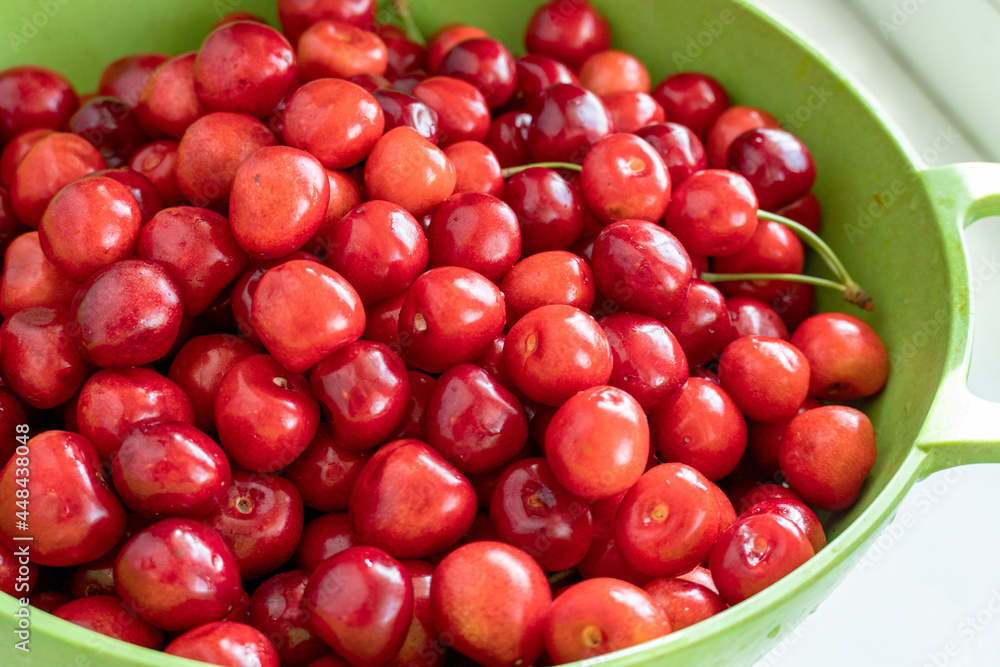 Green bowl full of ripe red sweet cherries close up Green bowl full of ripe red sweet cherries close up