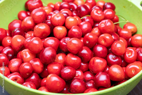 Green bowl full of ripe red sweet cherries close up