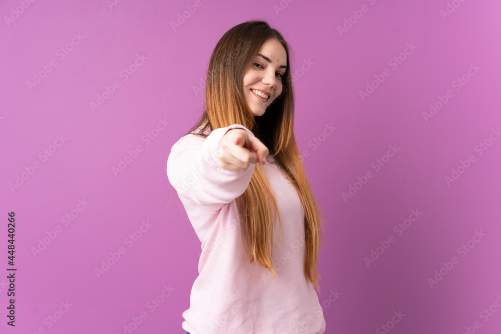 Young caucasian woman isolated on purple background pointing front with happy expression Young caucasian woman isolated on purple background pointing front with happy expression