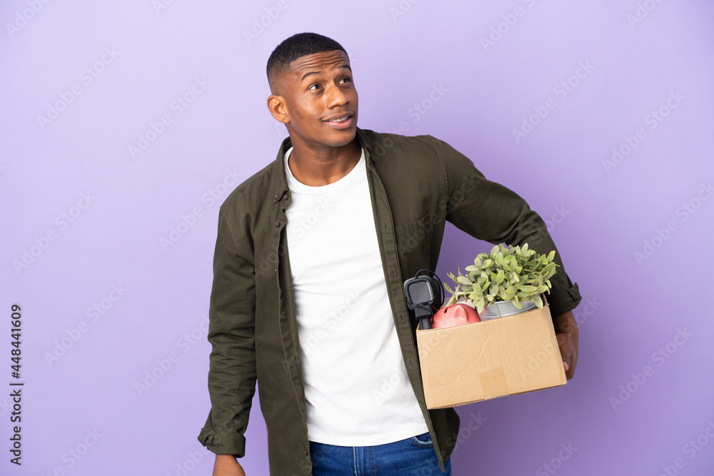 Latin man making a move while picking up a box full of things thinking an idea while looking up Latin man making a move while picking up a box full of things thinking an idea while looking up