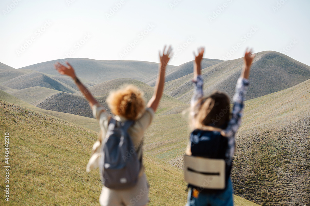 Exhilarated girl friends jumping on the spot amidst a beautiful hills scenery.