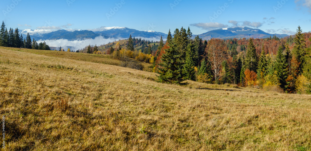 Late autumn mountain morning scene with snow covered tops in far and foggy clouds in valleys. Picturesque traveling, seasonal, nature and countryside beauty concept scene. Carpathians, Ukraine.