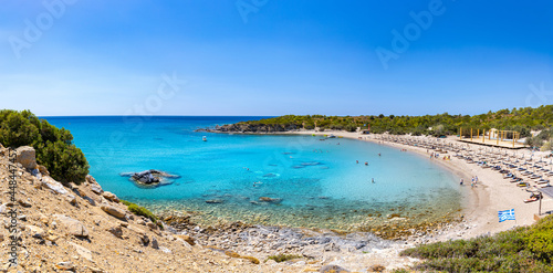 Fototapeta Naklejka Na Ścianę i Meble -  Crystal clear turquoise water in a Glystra beach. Cane umbrellas and sunbeds on an beach resort - vacation concept on Greece islands in Aegean and Mediterranean sea. Near Lindos at east Rhodes. Greece