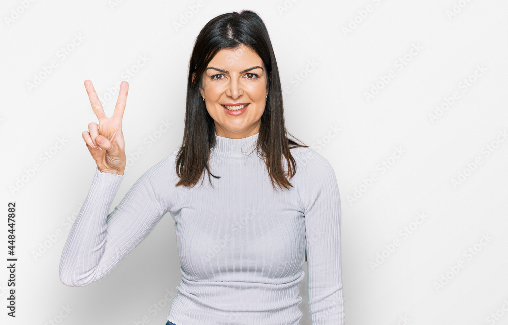 Beautiful brunette woman wearing casual clothes smiling looking to the camera showing fingers doing victory sign. number two. Beautiful brunette woman wearing casual clothes smiling looking to the camera showing fingers doing victory sign. number two.