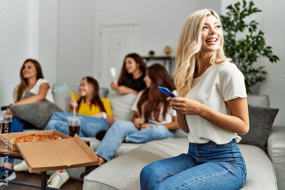 Obraz premium Group of young friends woman eating italian sitting on the sofa. Girl smiling and using smartphone at home.