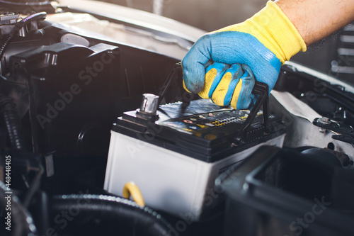 Technician is pulling up an car old battery for replacement