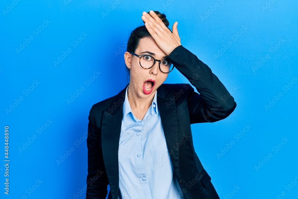 Young hispanic girl wearing business clothes and glasses surprised with hand on head for mistake, remember error. forgot, bad memory concept. - obrazy, fototapety, plakaty 