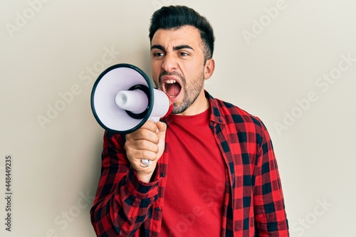 Hispanic man with beard screaming with megaphone