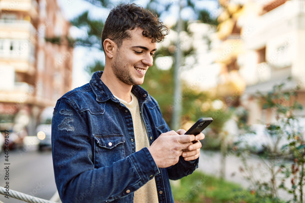 Young hispanic man smiling happy using smartphone at the city Young hispanic man smiling happy using smartphone at the city