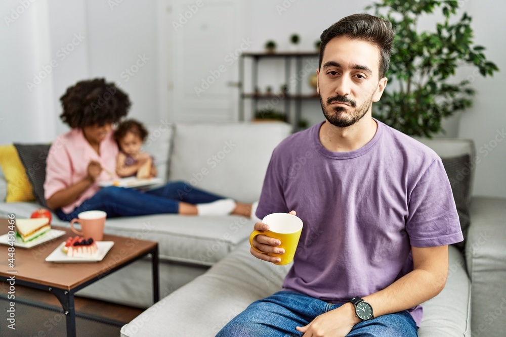 Hispanic father of interracial family drinking a cup coffee looking sleepy and tired, exhausted for fatigue and hangover, lazy eyes in the morning. Hispanic father of interracial family drinking a cup coffee looking sleepy and tired, exhausted for fatigue and hangover, lazy eyes in the morning.