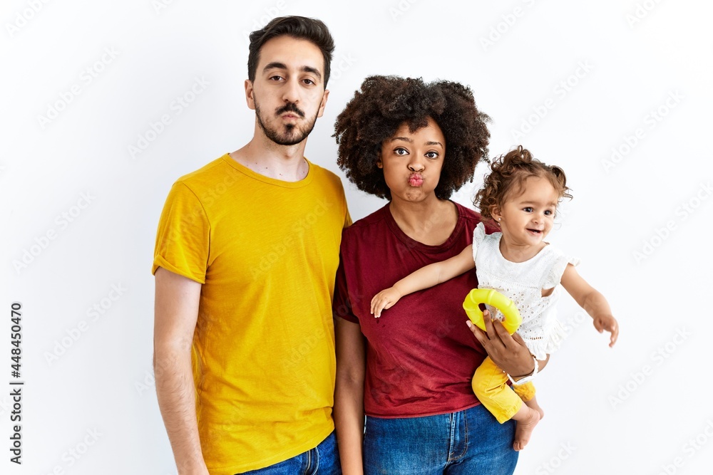 Interracial young family of black mother and hispanic father with daughter puffing cheeks with funny face. mouth inflated with air, crazy expression. Interracial young family of black mother and hispanic father with daughter puffing cheeks with funny face. mouth inflated with air, crazy expression.