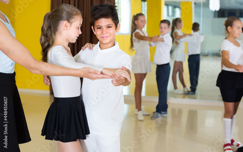 Teacher is showing to kids ren how to dance waltz in class.