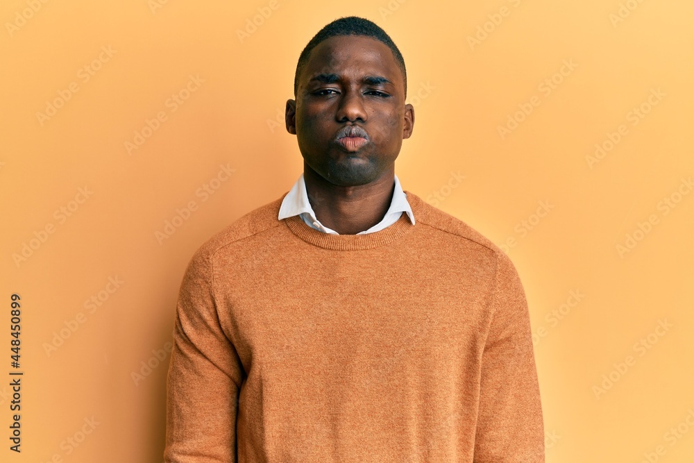 Young african american man wearing casual clothes puffing cheeks with funny face. mouth inflated with air, crazy expression.