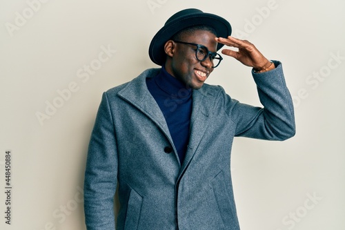 Young african american man wearing elegant style very happy and smiling looking far away with hand over head. searching concept.