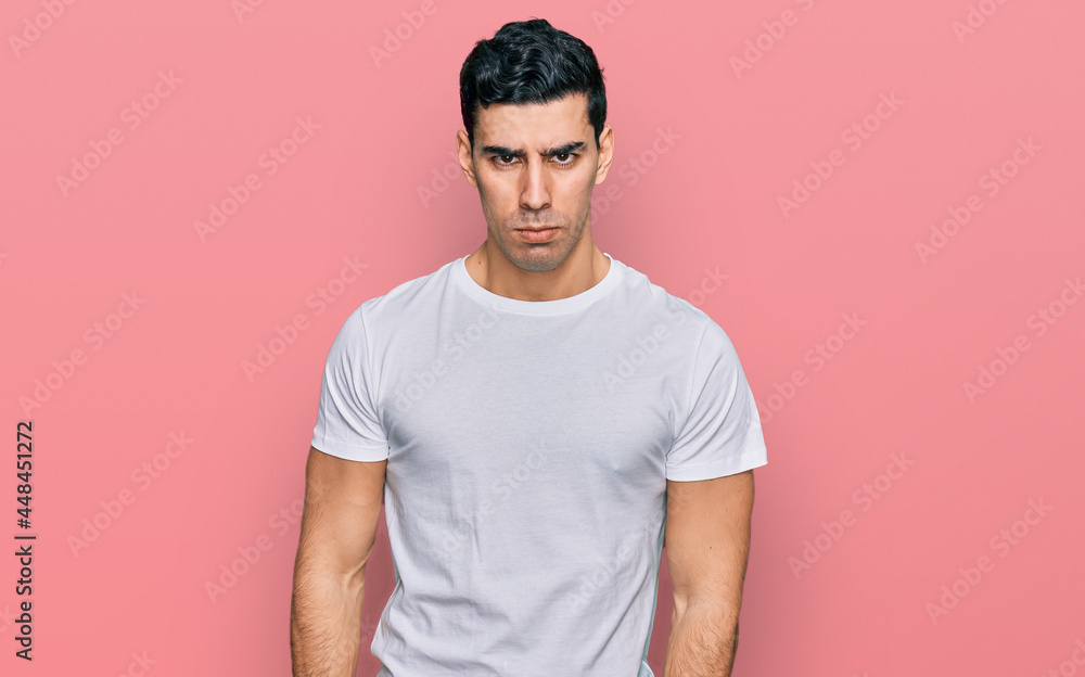 Handsome hispanic man wearing casual white t shirt skeptic and nervous, frowning upset because of problem. negative person. Handsome hispanic man wearing casual white t shirt skeptic and nervous, frowning upset because of problem. negative person.
