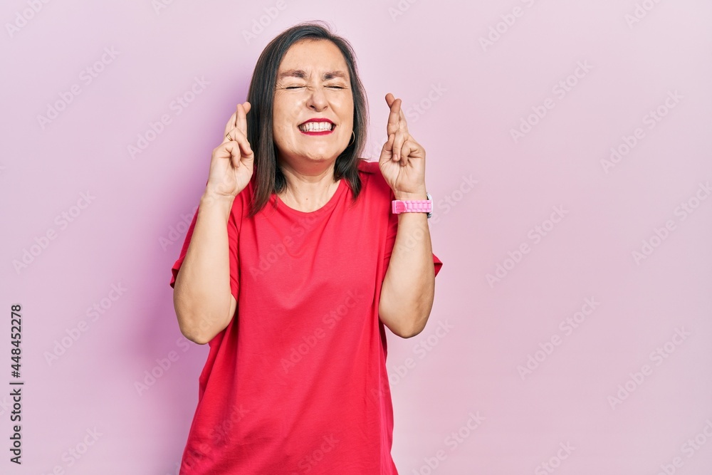 Middle age hispanic woman wearing casual clothes gesturing finger crossed smiling with hope and eyes closed. luck and superstitious concept. Middle age hispanic woman wearing casual clothes gesturing finger crossed smiling with hope and eyes closed. luck and superstitious concept.