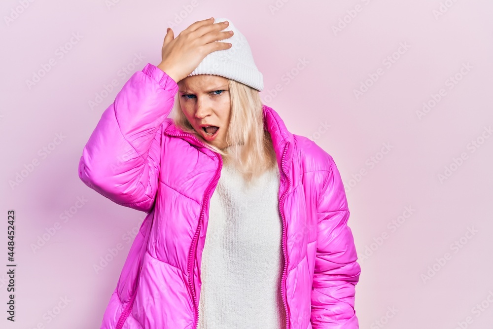Beautiful caucasian blonde woman wearing wool hat and winter coat surprised with hand on head for mistake, remember error. forgot, bad memory concept. Beautiful caucasian blonde woman wearing wool hat and winter coat surprised with hand on head for mistake, remember error. forgot, bad memory concept.