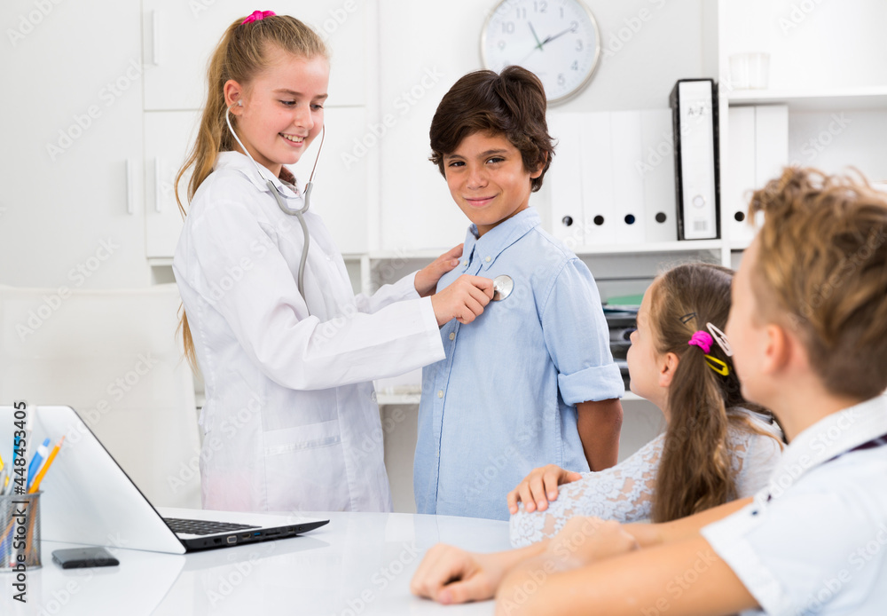 Fototapeta premium Medic girl with stethoscope with patient boy in the doctor's office