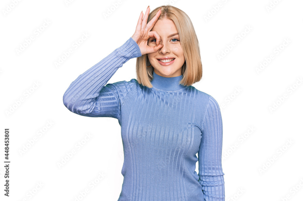 Young blonde woman wearing casual clothes smiling happy doing ok sign with hand on eye looking through fingers Young blonde woman wearing casual clothes smiling happy doing ok sign with hand on eye looking through fingers