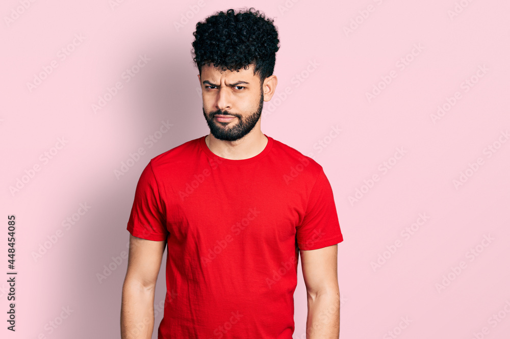 © Krakenimages.com - Young arab man with beard wearing casual red t shirt skeptic and nervous, frowning upset because of problem. negative person.