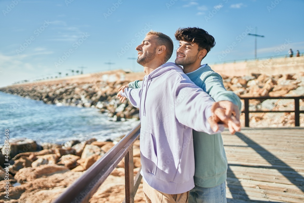Young gay couple breathing with arms opened at the beach. Young gay couple breathing with arms opened at the beach.