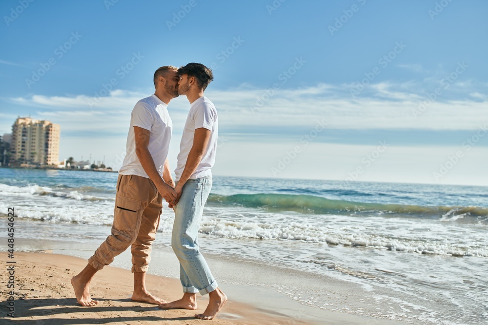 Young gay couple kissing at the beach.